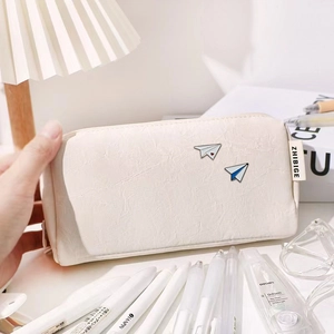 Detailed view of small white airplane enamel pins on a textured leather pencil case