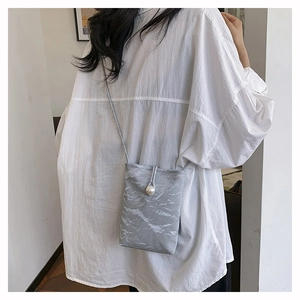 Détail du sac à téléphone plissé gris avec fermoir perle et fine bandoulière réglable