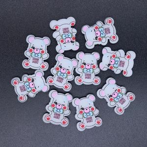 Flat lay of gray resin cartoon bear charms with 'HUG ME!' text for DIY craft accessories