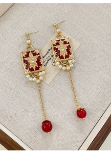Macro shot of French vintage pearl earrings with red resin and long gold tassels