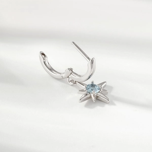 Minimalist silver North Star hoop earring with a light blue gemstone pendant in close-up