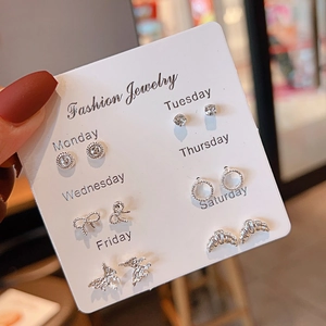 Detail of 6 pairs of silver earrings with bow and butterfly designs on a weekly card