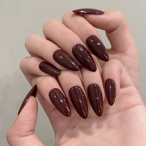 Close-up of deep wine red almond shaped press-on nails with a high glossy glass finish