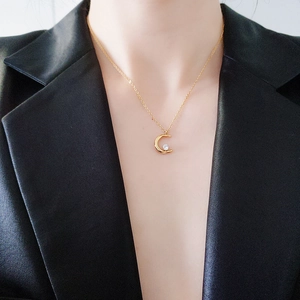 Golden crescent moon pendant necklace with zircon stone on model in black silk suit