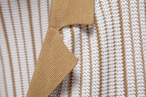 Close-up of the polo shirt collar featuring premium white and camel striped knit fabric