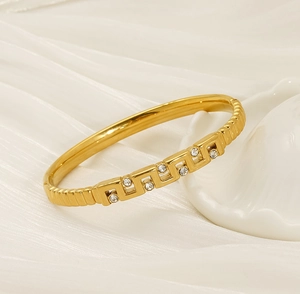 Gros plan du bracelet doré avec motif grec et oxydes de zirconium sur soie douce