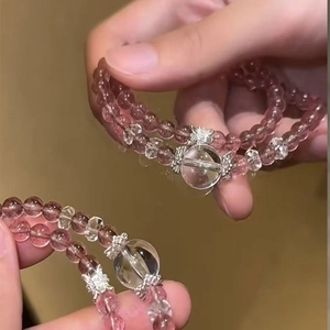 Detail of pink strawberry crystal beaded bracelet with silver floral clasp on hand