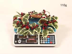Detail shot of Christmas wreath with berries and pinecones on a scale weighing 110g