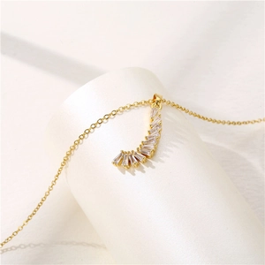 Elegant gold crescent necklace featuring sparkling zircon stones on a white display pedestal