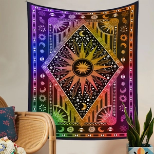 Detail eines Boho-Wandteppichs mit Sonnen- und Mondmuster an weißer Wand mit Korbstuhl