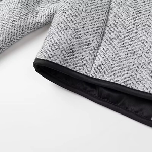 Close-up of luxury tweed jacket showing black trim details on cuffs and hemline