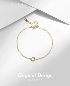 Macro shot of gold circular pendant with pavé set cubic zirconia on fine chain bracelet