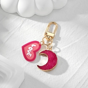 Detail of pink resin heart and moon charms with golden edges on a metal keychain