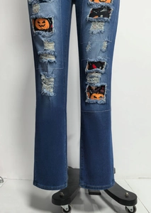 Detailansicht der Jeans mit Halloween-Kürbis-Patches und Knochen-Stickerei an den Knie-Rissen