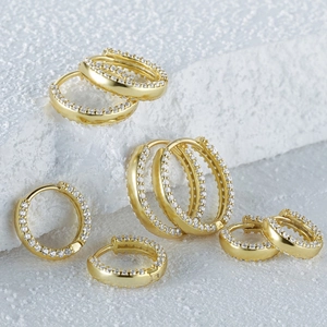 Macro detail of various sizes gold hoop earrings with pavé white zircon stones