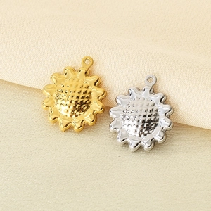 Macro shot of gold and silver hollow sunflower pendants on soft beige fabric background