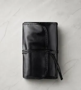 Black PU leather makeup brush roll with tri-fold strap design and smooth texture