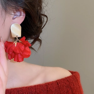 Close-up of elegant red fabric flower tassel earrings worn by a female model