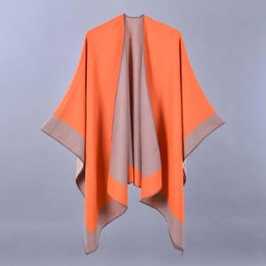 Detail view of a double-sided knitted poncho showing vibrant orange and light brown grey fabric