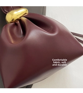 Detailed view of dark red pleated leather bag with a premium gold metal buckle