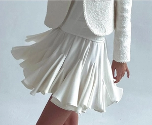 Détail d'un ensemble veste en tweed blanc et mini-jupe plissée avec tissu texturé