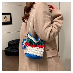 Detail of crochet bucket bag with cherry pattern and elegant pearl shoulder strap