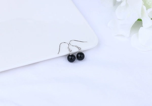 Close-up of black agate drop earrings with S925 silver hooks on a white ceramic plate
