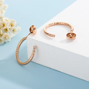 Dettaglio degli orecchini a forma di C in oro rosa con superficie martellata