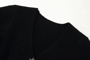 Detail of the black V-neck knit sweater showing the soft texture and wool yarn material