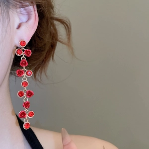 Close-up of long red rose tassel earrings with crystals and gold-tone drop design