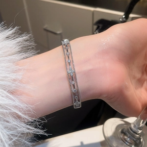 Detailed view of silver openwork bangle with white cubic zirconia on female wrist