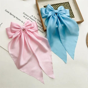 Detail of pink and blue satin bow hair clips with long ribbon streamers on magazine