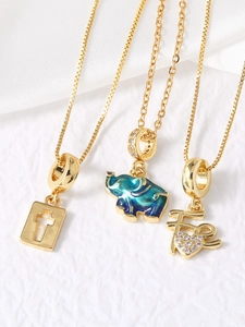 Macro shot of 18k gold plated elephant pendant, cross and heart charm necklaces