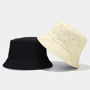 Detail of reversible daisy floral and plain black cotton bucket hats for sun protection