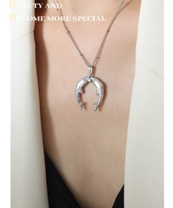 Detail of silver dolphin horseshoe pendant necklace with beaded chain on model neck