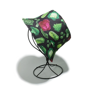 Close-up of vibrant vegetable print bucket hat on minimalist black iron stand