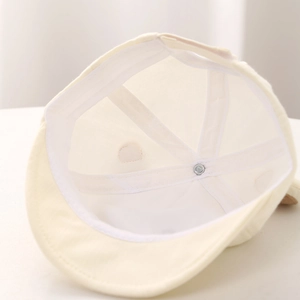 Detail view of cotton baby hat interior showing six-panel stitching and metal rivet