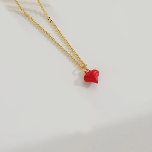 Detail view of a gold O-chain necklace featuring a glossy red enamel heart-shaped pendant