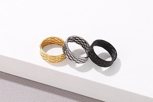 Detail of three textured fish-pattern rings in gold, silver, and black finishes