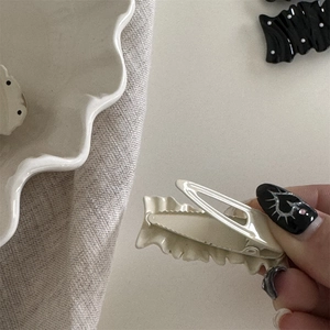 Detail of cream wavy hair clip with metal duckbill clip on minimalist linen cloth