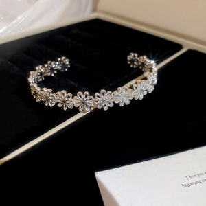 Detail of silver daisy flower bangle displayed in a premium black jewelry gift box