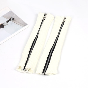 Detail view of white knitted leg warmers with black zipper and triangular puller