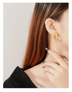 Detailed close-up of a gold beaded hoop earring with sparkling white zircon stones