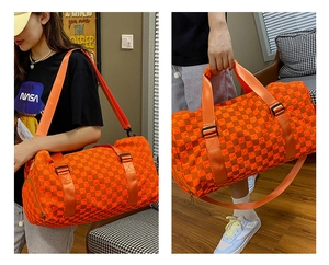 Detail view of large orange checkerboard travel bag shown with hand and shoulder straps