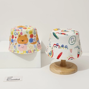 Detail of baby sun hats featuring colorful cartoon bear and rainbow graffiti prints