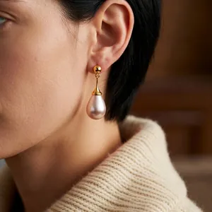 Eleganti orecchini a goccia con perle rosa e metallo dorato su una modella donna