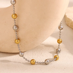 Detail of 18K gold and silver bead layered necklace on a textured stone display