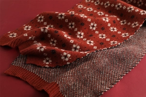 Close-up of a festive red Christmas knit scarf with white snowflake patterns and texture