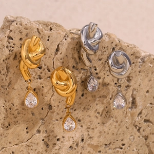 Dettaglio di orecchini a nodo in oro 18K e argento con zircone a goccia su base in pietra