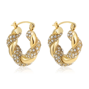 Macro detail of gold-plated twisted hoop earrings with shimmering crystal pavé setting
